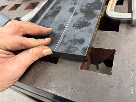 The sheet metal isn't folded. The edges of the sheet are flush with the outsides of the bar hiding it